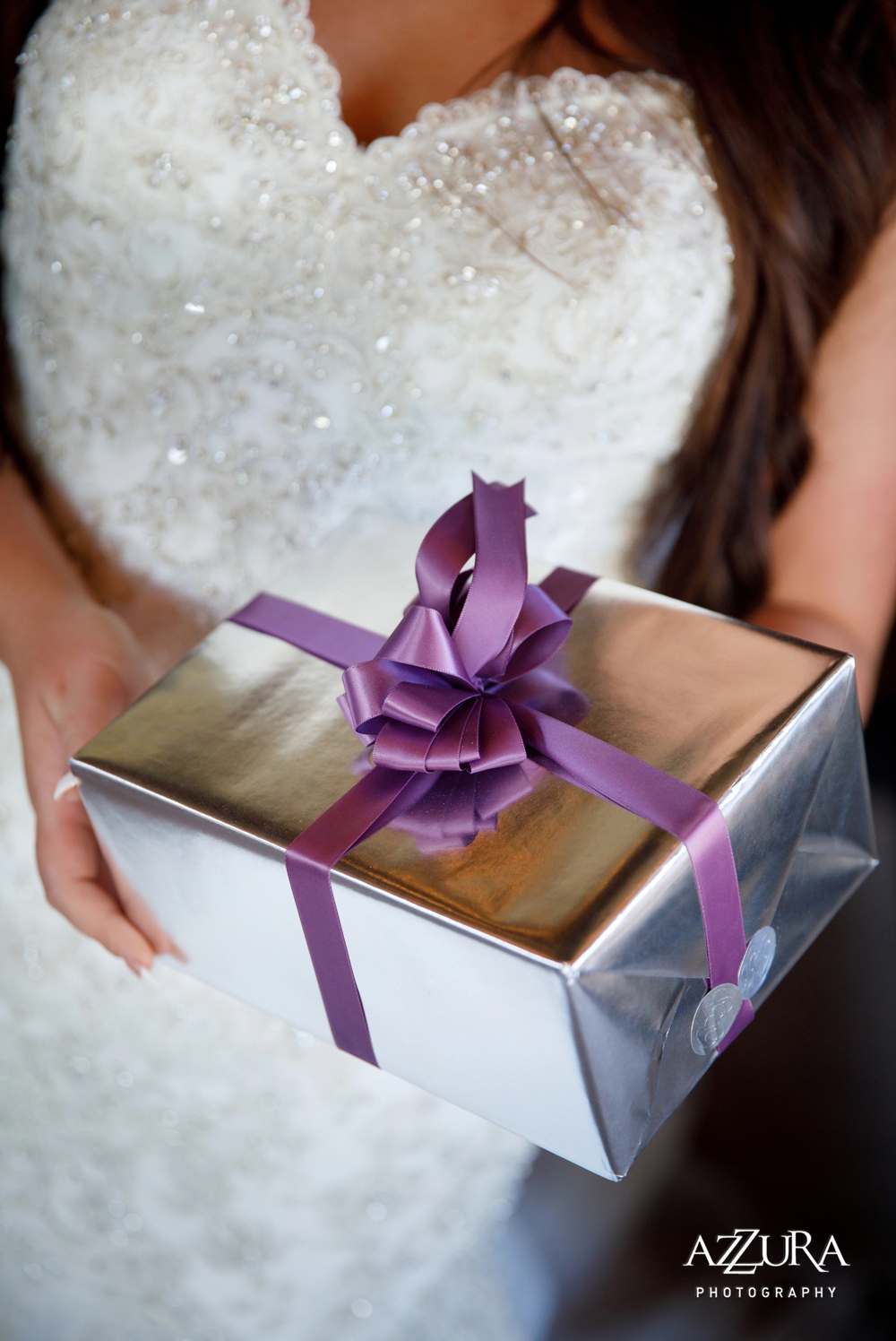 bride-holding-gift-wrapped-in-silver-paper-with-a-purple-ribbon